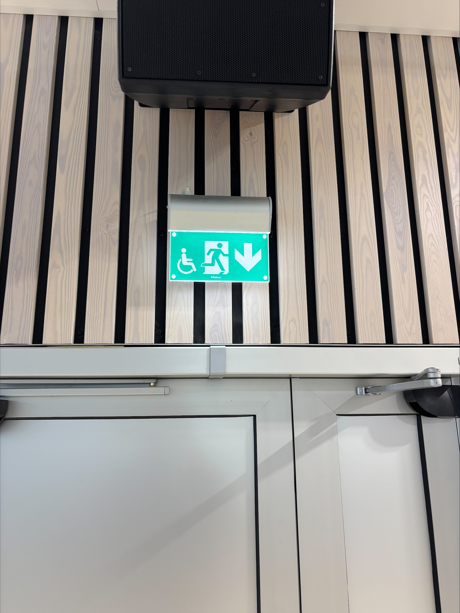 Närbild på en tekniker med blå handskar som arbetar med ett moderkort under en ljus ringlampa i en svagt upplyst miljö.